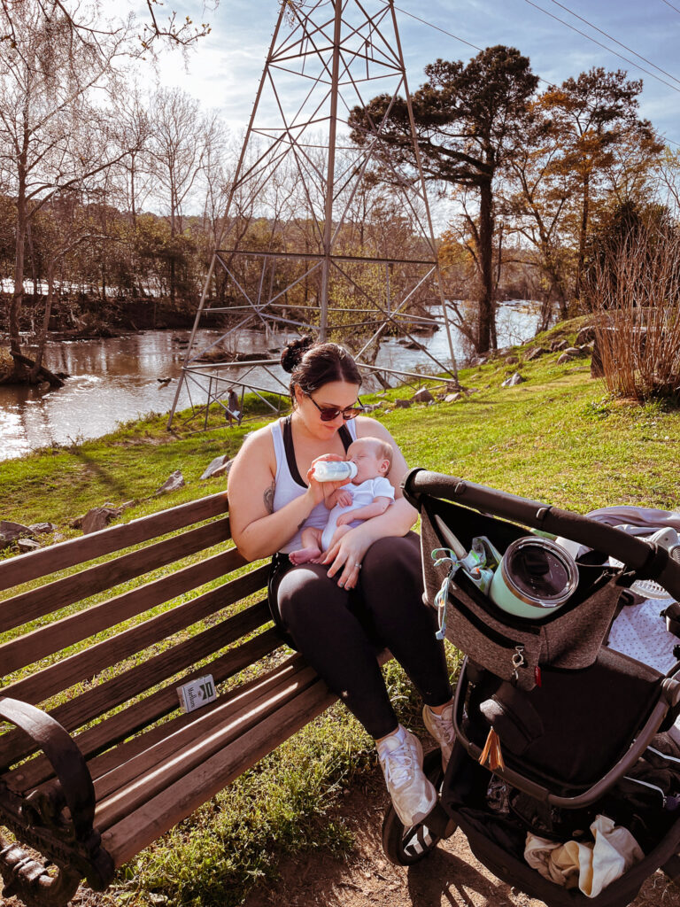 mom bottle feeding baby on the park bench