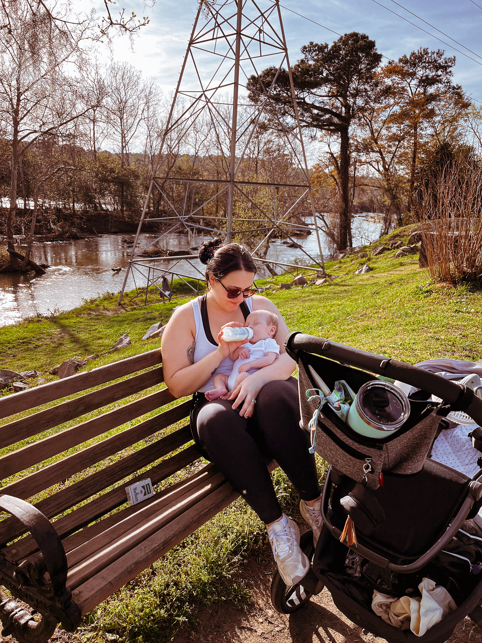 mom bottle feeding baby on the park bench