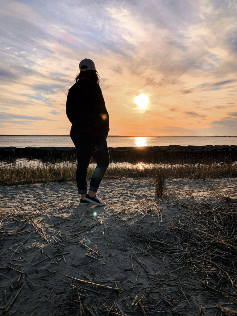Woman silhouette taking a slow moment on the beach watching the sunset