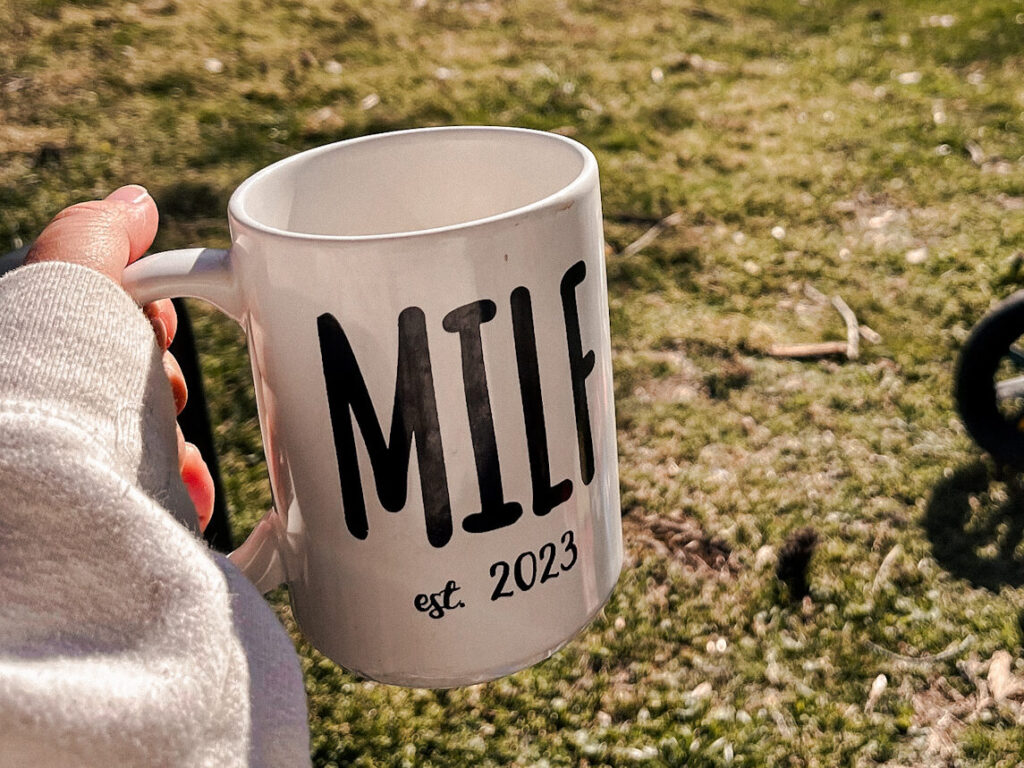Morning momma motivation cup of coffee in a MILF cup with toddler riding bike in a spiked green helmet
