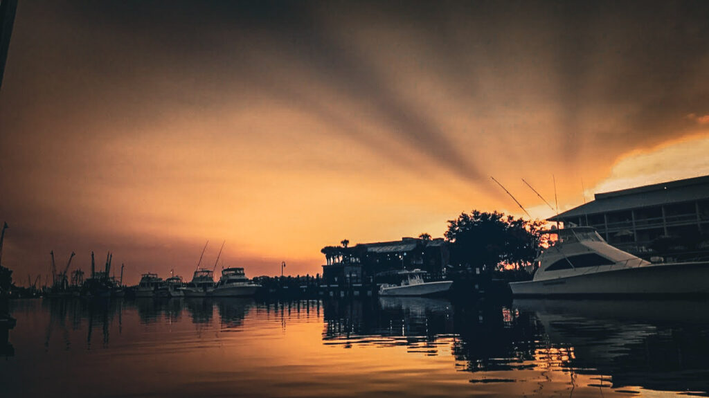 Calm creek at sunset with boats docked, creating a peaceful and grounding scene