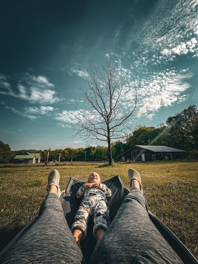 mom resting on cot outside with toddler