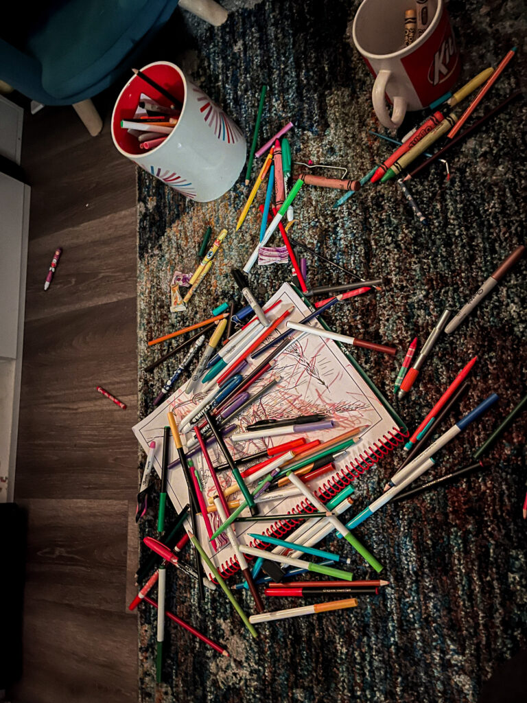 toddler mess of markers and coloring books on the floor 
