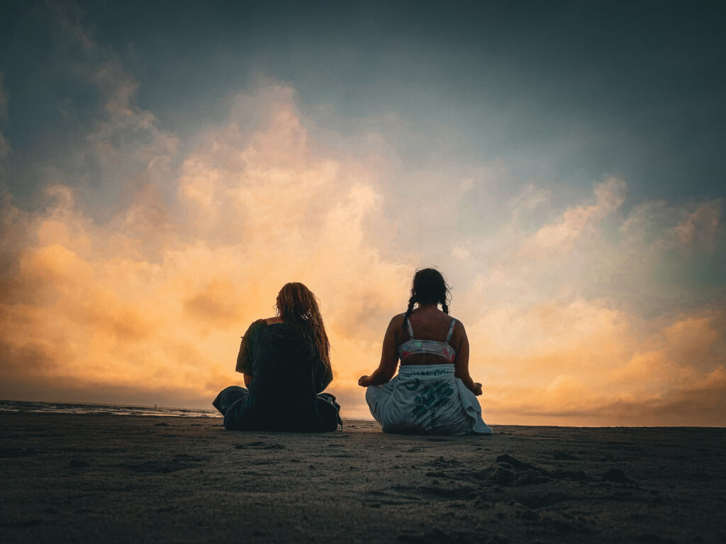 women resting on beach while meditating